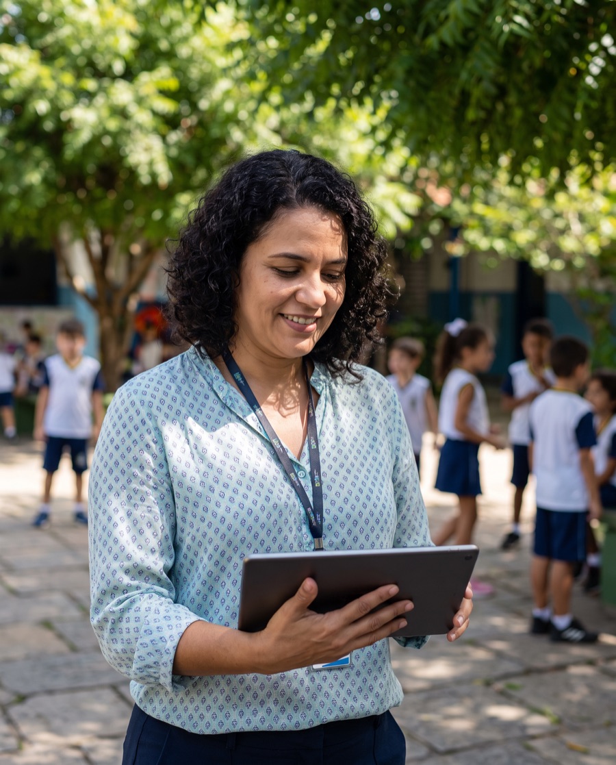 Coordenadora de atividades olhando um tablet no pátio da escola